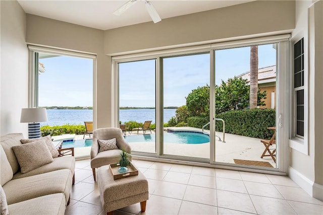 sunroom / solarium featuring ceiling fan and a water view