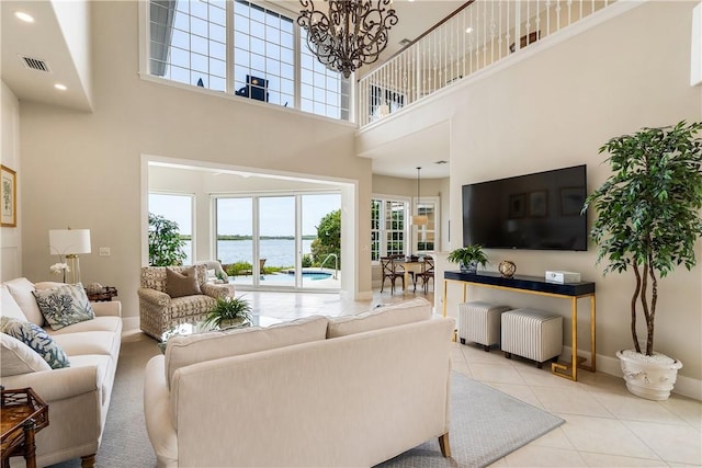 living room featuring light tile patterned flooring, a towering ceiling, and a chandelier