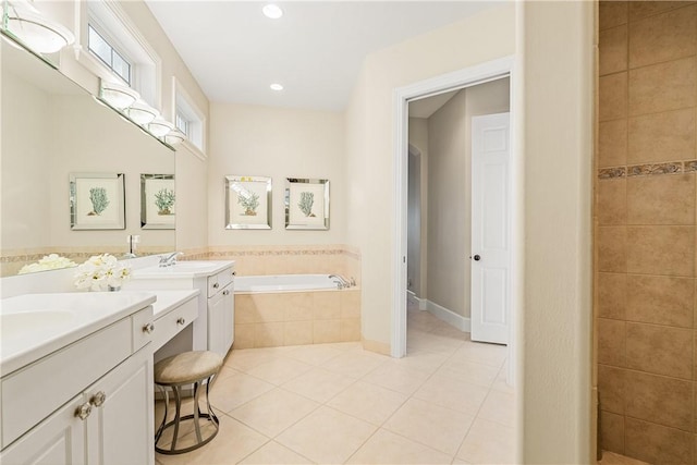 bathroom with tiled tub, vanity, and tile patterned flooring