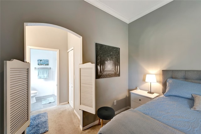 carpeted bedroom with connected bathroom and ornamental molding