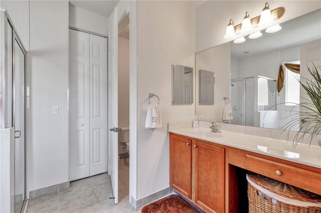 bathroom with tile patterned floors, a shower with door, and vanity