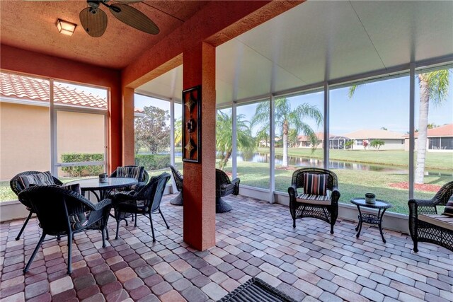 sunroom / solarium featuring ceiling fan and a water view