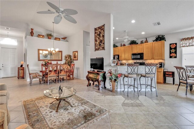 tiled living room featuring ceiling fan with notable chandelier and vaulted ceiling