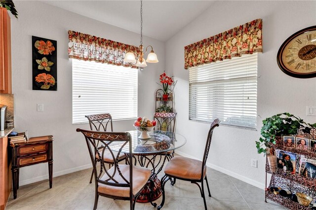 dining room with light tile patterned flooring, lofted ceiling, and an inviting chandelier