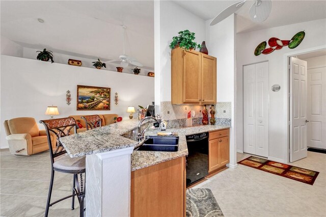 kitchen featuring ceiling fan, dishwasher, sink, light stone counters, and kitchen peninsula