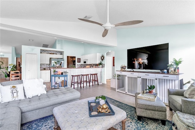 living room with ceiling fan, light tile patterned floors, and high vaulted ceiling