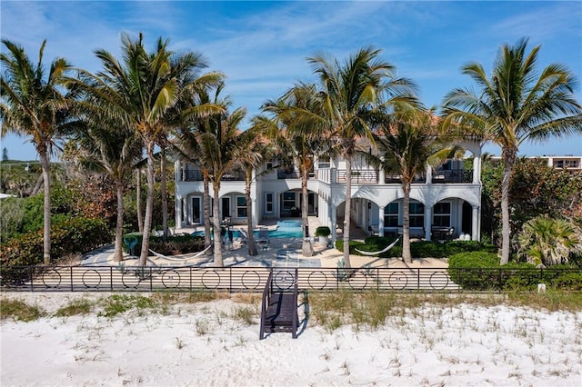 back of house featuring an outdoor pool, a patio, a balcony, and fence