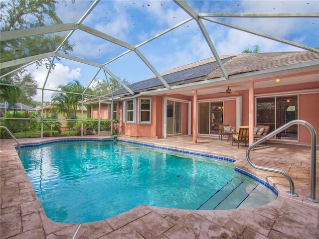 view of pool featuring glass enclosure, ceiling fan, and a patio