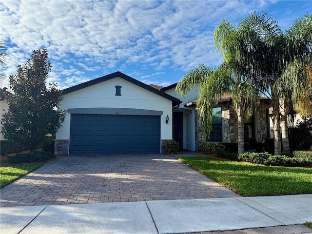 ranch-style home featuring a garage, stone siding, decorative driveway, and stucco siding