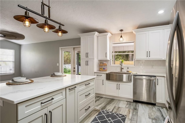 kitchen featuring stainless steel appliances, tasteful backsplash, pendant lighting, and white cabinets