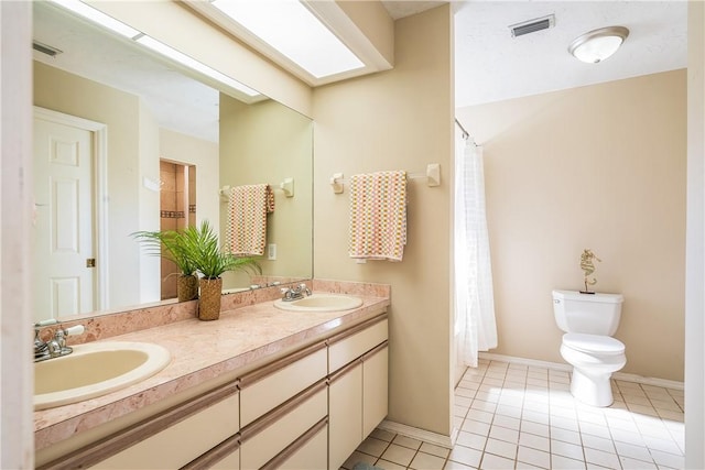 bathroom with vanity, toilet, a skylight, and tile patterned flooring