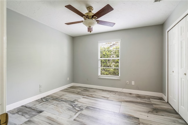 unfurnished bedroom with ceiling fan and a closet