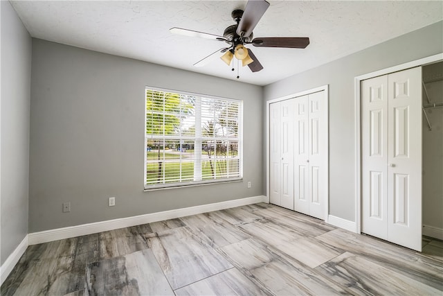 unfurnished bedroom featuring multiple closets and ceiling fan