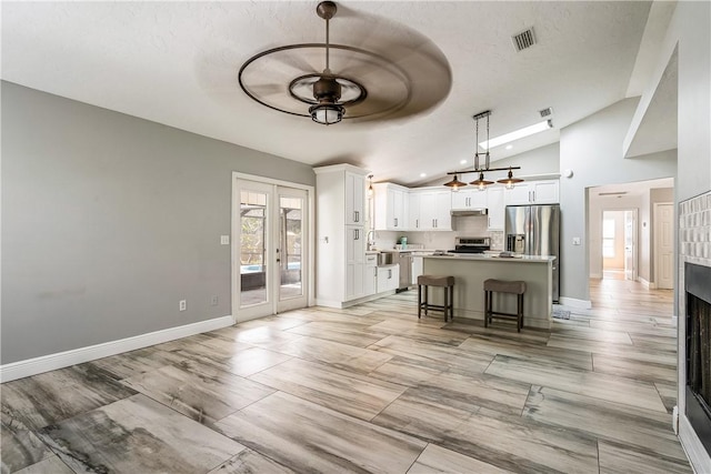 kitchen featuring white cabinetry, a kitchen island, a kitchen bar, and decorative light fixtures