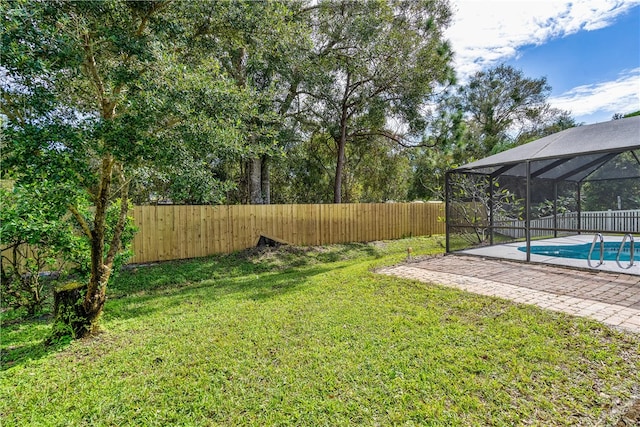 view of yard featuring a fenced in pool and glass enclosure