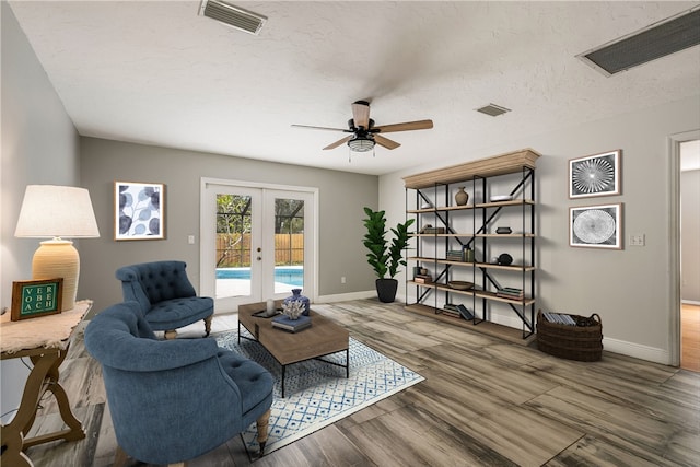 living room with wood-type flooring, ceiling fan, a textured ceiling, and french doors