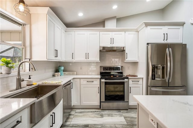 kitchen with stainless steel appliances, vaulted ceiling, and white cabinetry