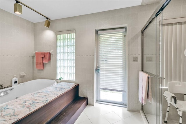 8560 De Haviland Ct, Vero Beach, FL 32968 - bathroom featuring a shower stall, tile walls, a garden tub, and tile patterned flooring