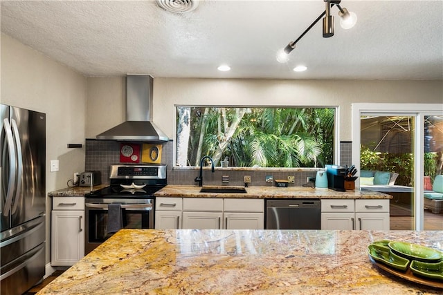 kitchen with sink, wall chimney exhaust hood, decorative backsplash, white cabinetry, and stainless steel appliances