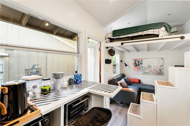 kitchen featuring vaulted ceiling with beams and hardwood / wood-style floors