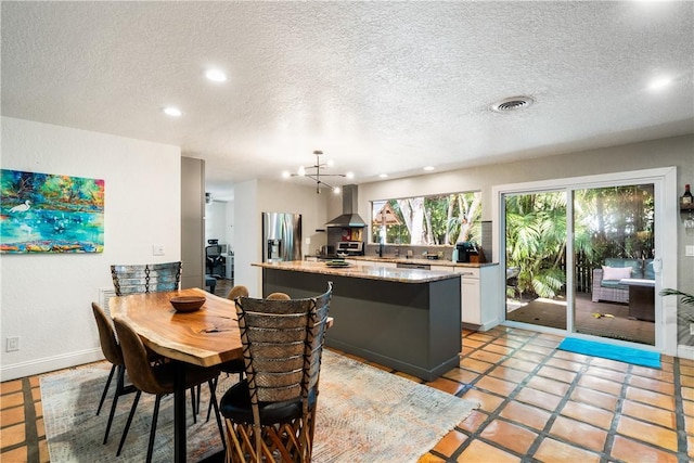 tiled dining space featuring a textured ceiling and an inviting chandelier