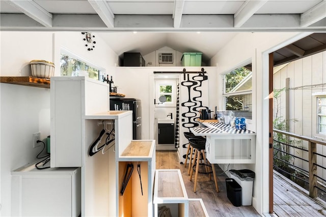 kitchen featuring beam ceiling, plenty of natural light, wood-type flooring, and sink