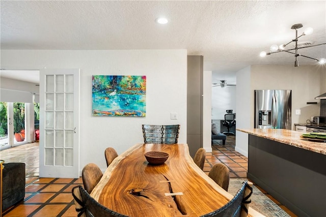 dining area with french doors, light tile patterned floors, a textured ceiling, and a notable chandelier