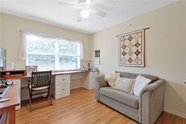 office space with ceiling fan, built in desk, and light hardwood / wood-style floors