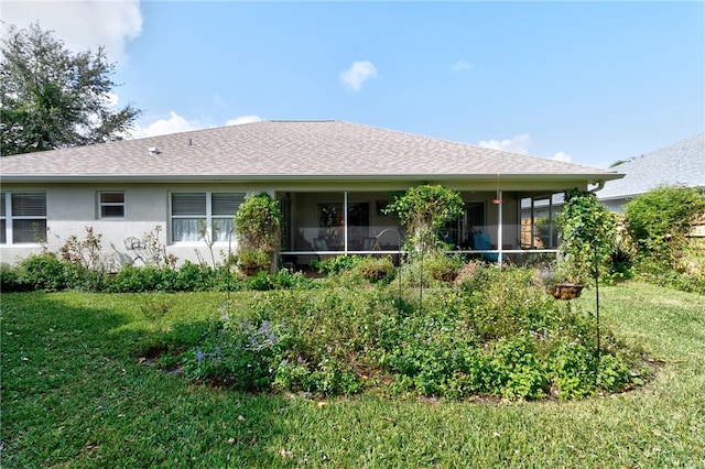 rear view of property featuring a lawn and a sunroom