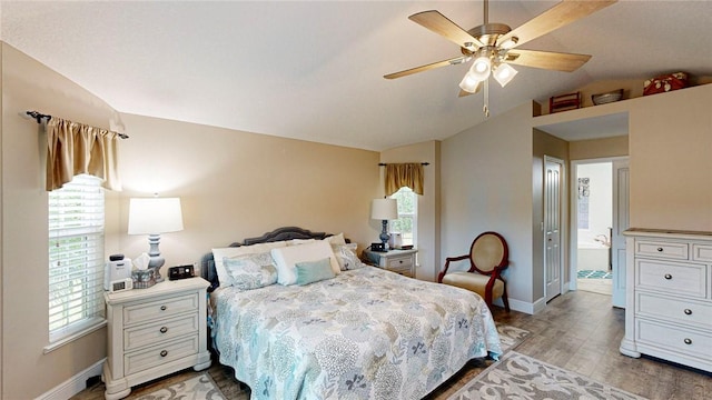 bedroom featuring connected bathroom, ceiling fan, wood-type flooring, vaulted ceiling, and multiple windows