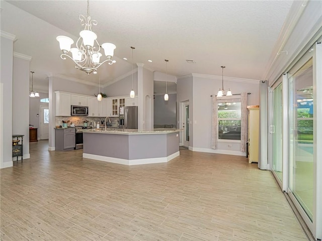 kitchen with a kitchen island with sink, hanging light fixtures, vaulted ceiling, white cabinetry, and stainless steel appliances