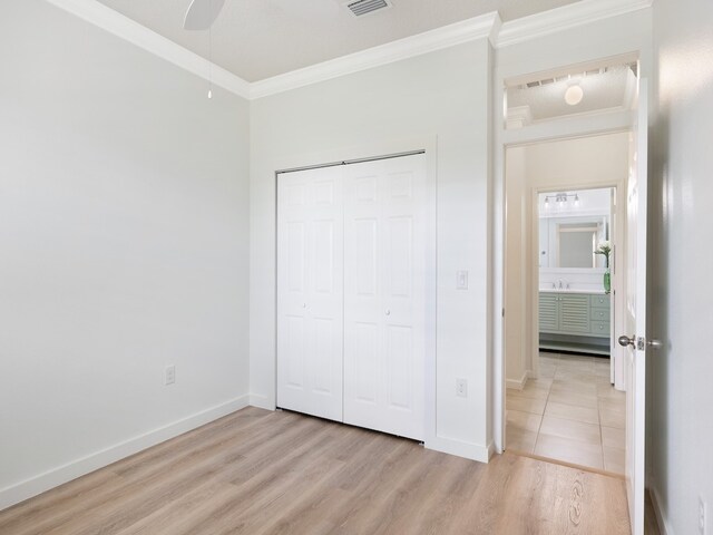 unfurnished bedroom featuring light hardwood / wood-style floors, ceiling fan, a closet, and crown molding