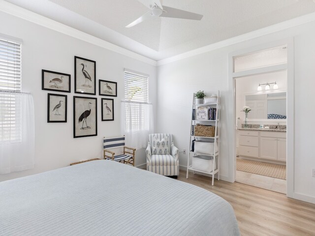 bedroom featuring ceiling fan, crown molding, light hardwood / wood-style floors, and ensuite bath