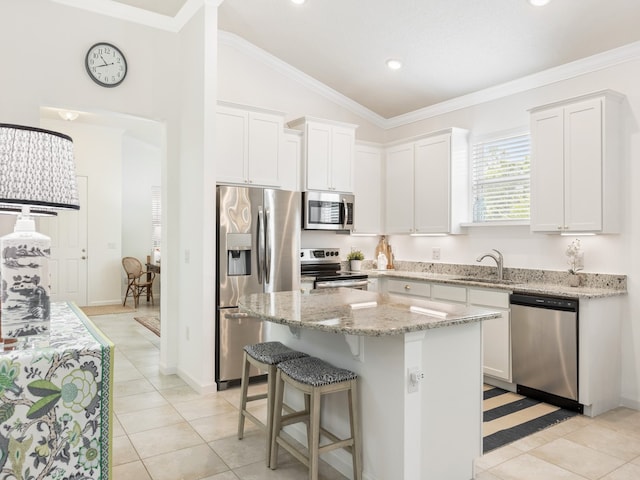 kitchen with stainless steel appliances, sink, white cabinets, lofted ceiling, and a center island