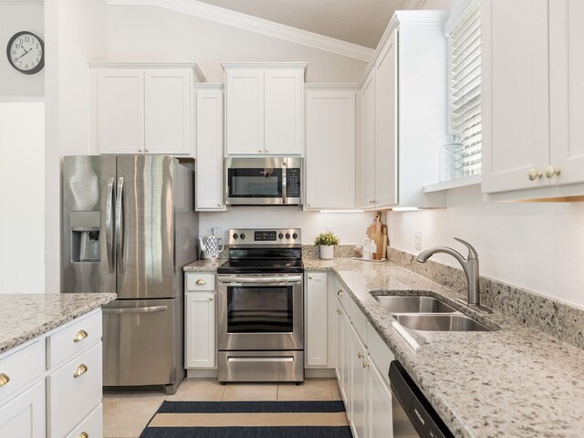 kitchen featuring white cabinetry, sink, appliances with stainless steel finishes, ornamental molding, and lofted ceiling