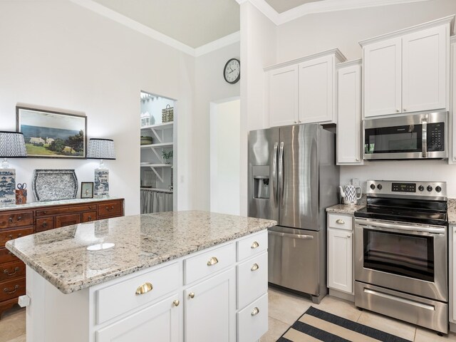 kitchen with white cabinets, crown molding, a kitchen island, light stone countertops, and appliances with stainless steel finishes