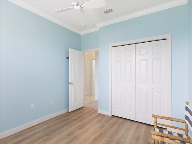 unfurnished bedroom with light wood-type flooring, ceiling fan, crown molding, and a closet