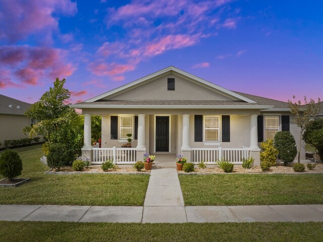 view of front of home with covered porch and a yard