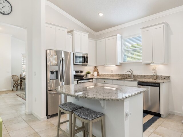 kitchen featuring stainless steel appliances, sink, lofted ceiling, a center island, and white cabinets