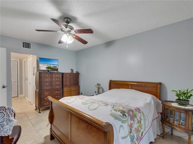 tiled bedroom with ceiling fan and a textured ceiling