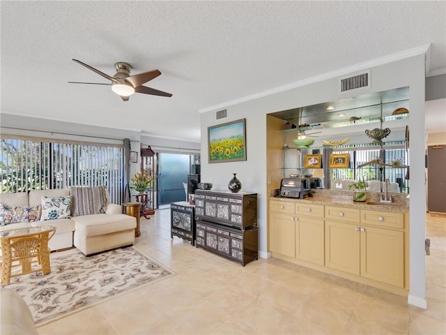 living room featuring crown molding, ceiling fan, a healthy amount of sunlight, and a textured ceiling