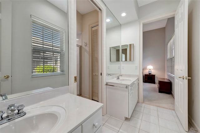 bathroom with a closet, tile patterned floors, two vanities, and a sink