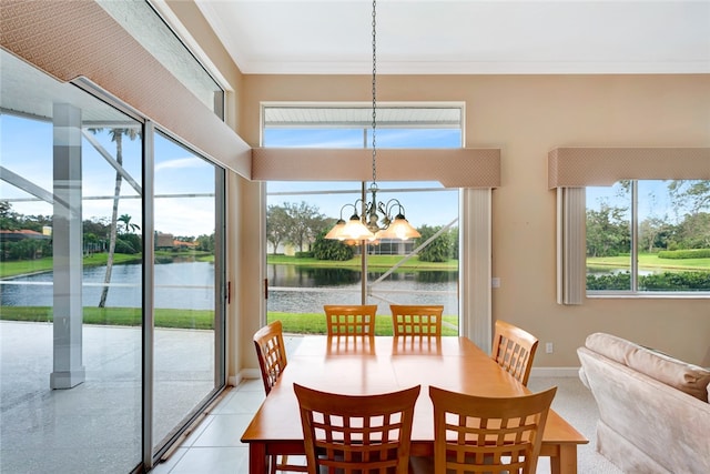 dining space featuring a notable chandelier, ornamental molding, a healthy amount of sunlight, and a water view