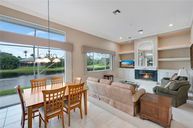 living area with a high end fireplace, visible vents, built in shelves, a water view, and a notable chandelier