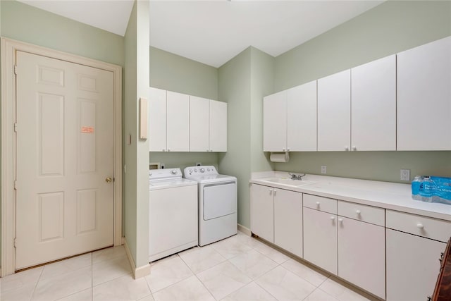 clothes washing area with light tile patterned floors, baseboards, cabinet space, a sink, and washer and dryer