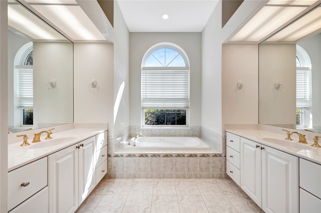 full bath with tile patterned flooring, two vanities, a bath, and a sink