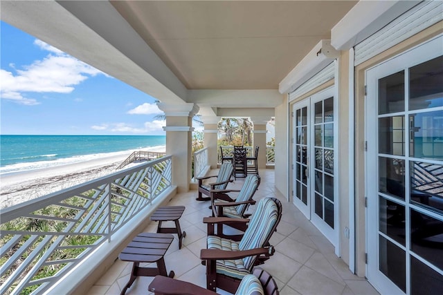 balcony with a view of the beach, french doors, and a water view