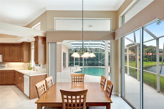 dining area with light tile patterned floors, a chandelier, ornamental molding, and a sunroom