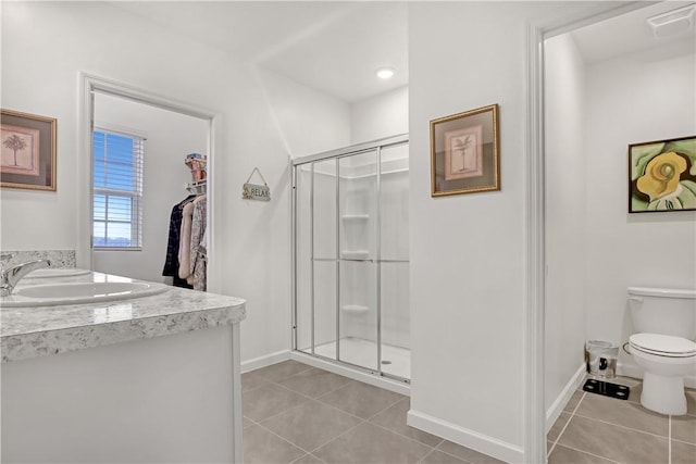 bathroom featuring toilet, a shower with shower door, tile patterned floors, and vanity