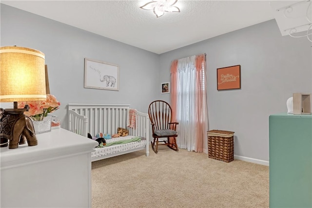 bedroom with a textured ceiling, carpet, and a nursery area